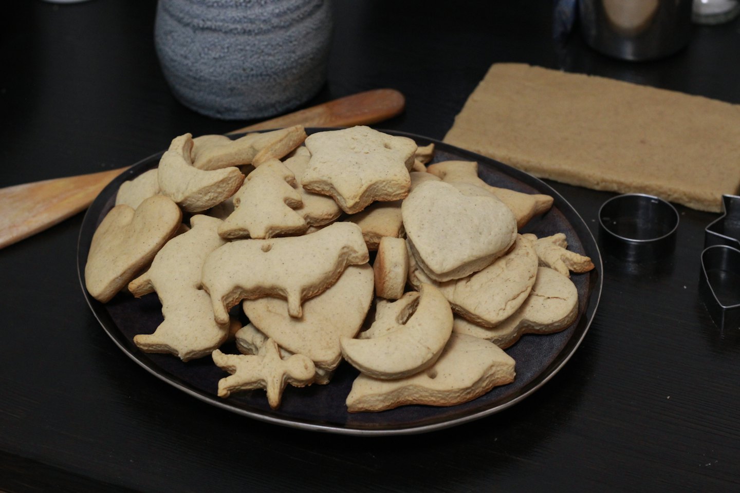 Assorted fresh cookies and cutters on a wooden table.